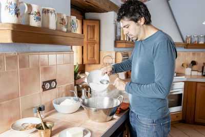 Middle aged man mixing flour, sugar and other ingredients to cook