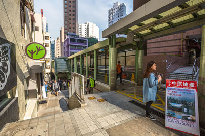 People walking on footpath by buildings in city