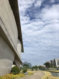 Low angle view of bridge by buildings against sky