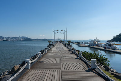 Pier over river against clear blue sky