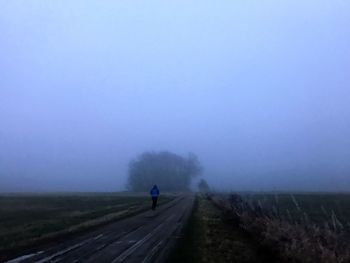 Man walking on road in foggy weather