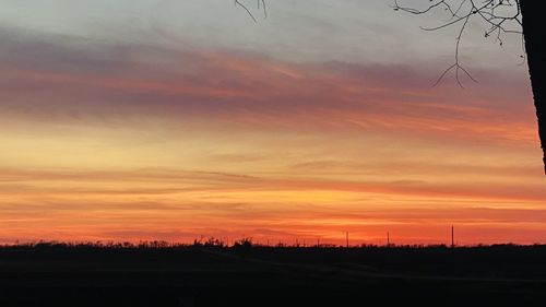 Scenic view of dramatic sky over silhouette landscape during sunset