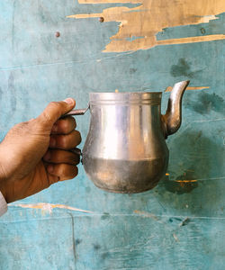 Cropped image of tea pot against wooden wall