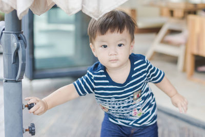 Portrait of cute boy holding knob at home