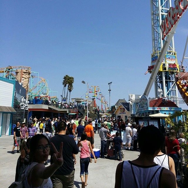 clear sky, men, lifestyles, person, leisure activity, built structure, large group of people, architecture, building exterior, copy space, blue, city, amusement park, sky, crane - construction machinery, arts culture and entertainment, rear view, outdoors, construction site