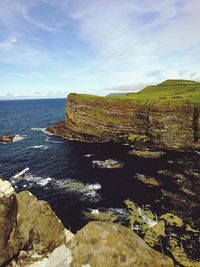 Scenic view of rocks by sea against sky