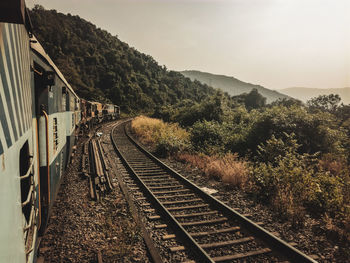 Railroad tracks by mountain against sky