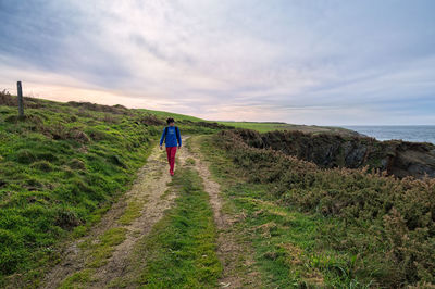 Man walking on dirt track against sky