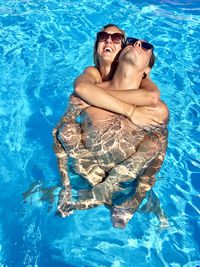 High angle view of man piggybacking woman in swimming pool