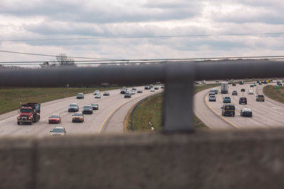 Vehicles on road against cloudy sky