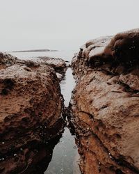 Rock formations in sea against clear sky