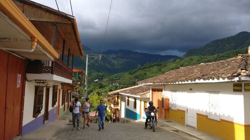 People on road amidst buildings against sky