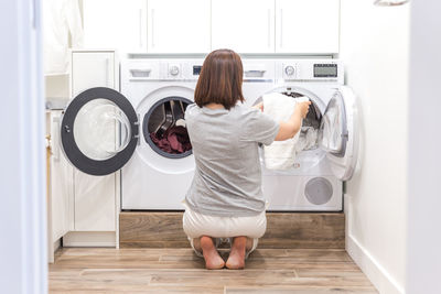 Rear view of woman removing clothes from washing machine