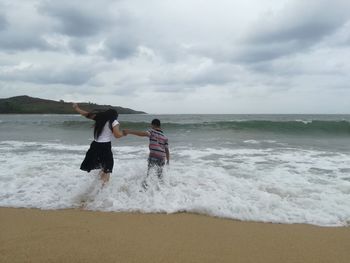 Rear view of people on beach against sky