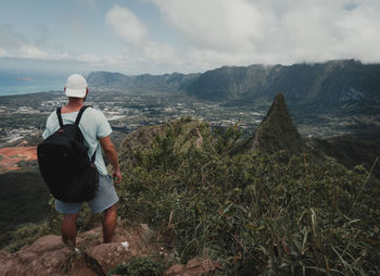 Rear view of man looking at mountain against sky