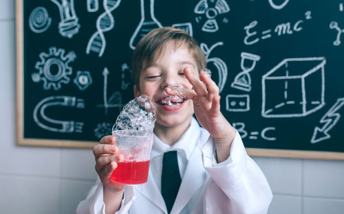 Boy wearing lap coat while standing in classroom