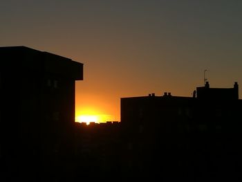 Silhouette buildings against orange sky