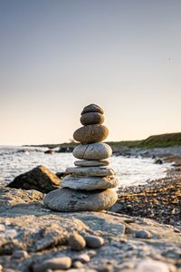 Stack of stones on beach against sky during sunset