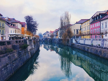 Reflection of buildings and trees in canal against sky