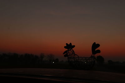 Silhouette of bicycle on field against orange sky