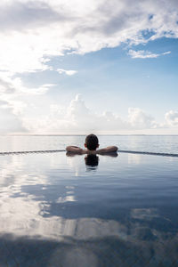 Little kid looking the ocean from a infinity pool