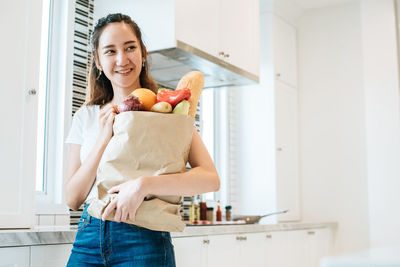 Smiling woman with food standing at home