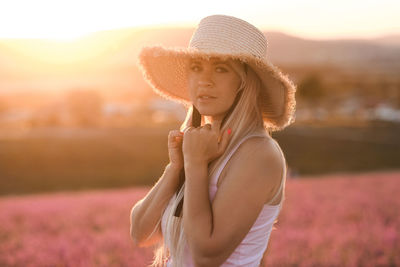 Beautiful smiling woman wear straw hat and dress standing in purple lavender flower field outdoor