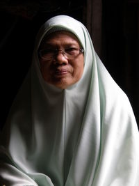 Portrait of woman wearing hijab against black background