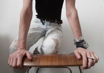 Midsection of woman holding hands against wall