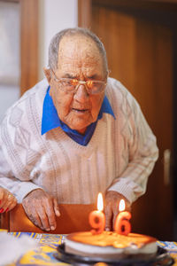 Senior man blowing birthday candles on cake 