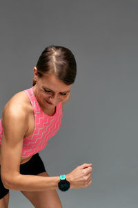 Side view of young woman exercising against white background