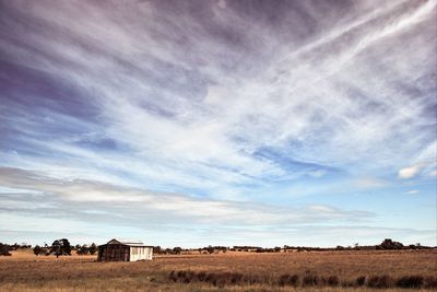 View of field against cloudy sky