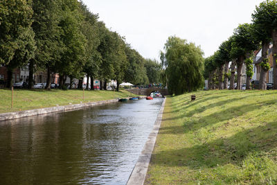 People in park by canal against sky