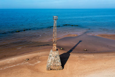 Abandoned ruins of kurmrags lighthouse on the baltic coast, aerial view, long shadow on a sunny day