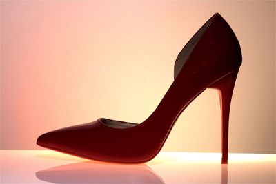 Close-up of red high heels on table against white background
