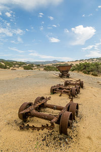 High angle view of abandoned rusty vehicle parts on field against sky