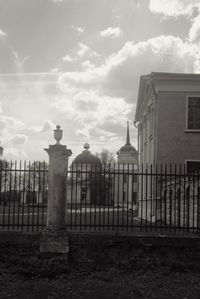 Building by fence against sky