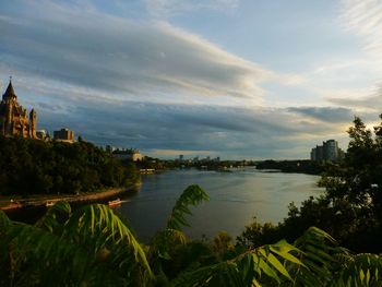 Scenic view of river by buildings against sky