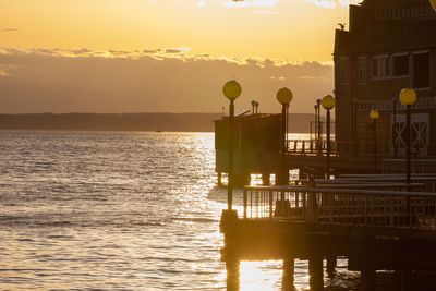 Silhouette of pier and water as sun sets in background