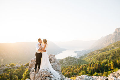 Couple standing on mountain against sky