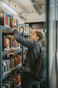 Young students searching book together in library at university