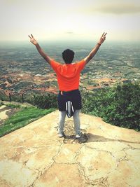 Rear view of man with arms outstretched standing on landscape