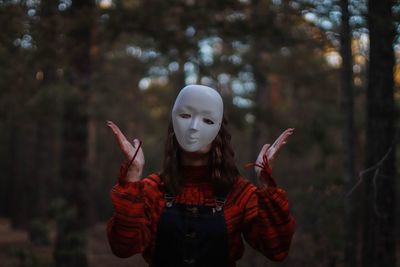 Woman wearing mask while standing in forest