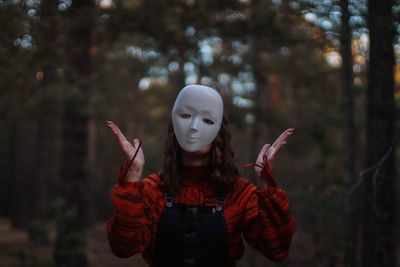 Portrait of woman with mask standing against trees
