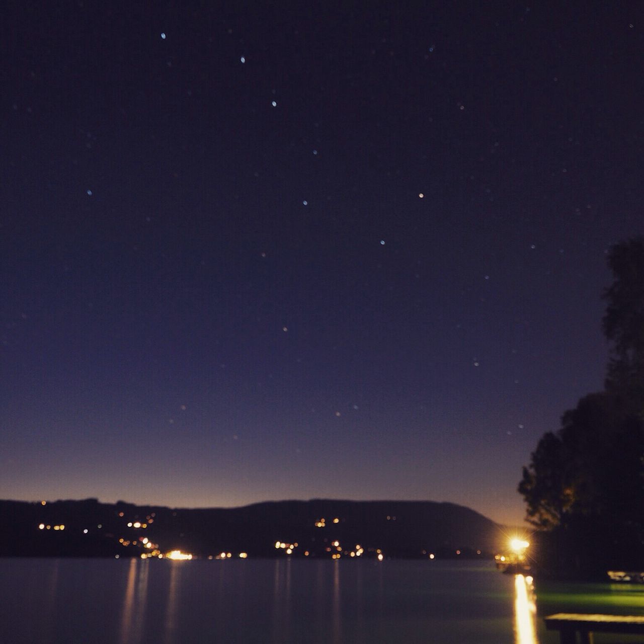 night, illuminated, reflection, scenics, water, tranquil scene, star - space, waterfront, tranquility, clear sky, dark, beauty in nature, sky, nature, distant, mountain, outdoors, majestic, standing water, no people, star field, non-urban scene, galaxy