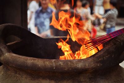 Close-up of igniting incenses from fire in pot at temple