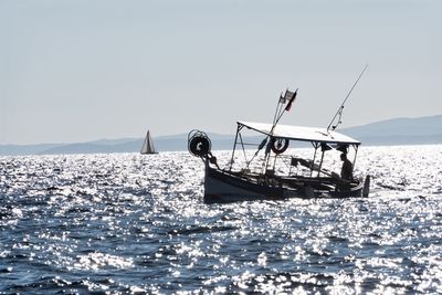 Fisherman in sea against clear sky