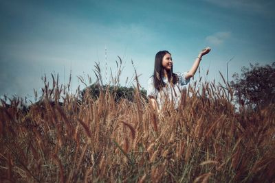 Portrait of young woman on field against sky