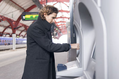 Man using ticket machine at train station