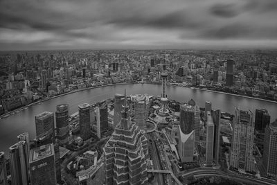 High angle view of city buildings against cloudy sky